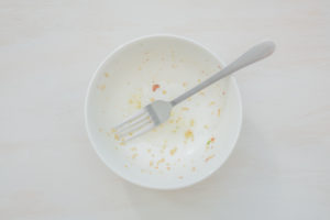 Rice scraps with vegetables in a white bowl on a white table